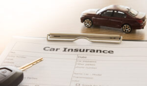 Car insurance application form with car model and key remote on desk.